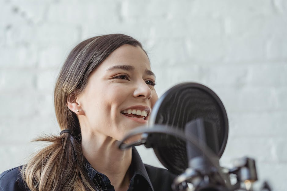 An image showing a host with headphones on, speaking into a microphone in a podcast studio.