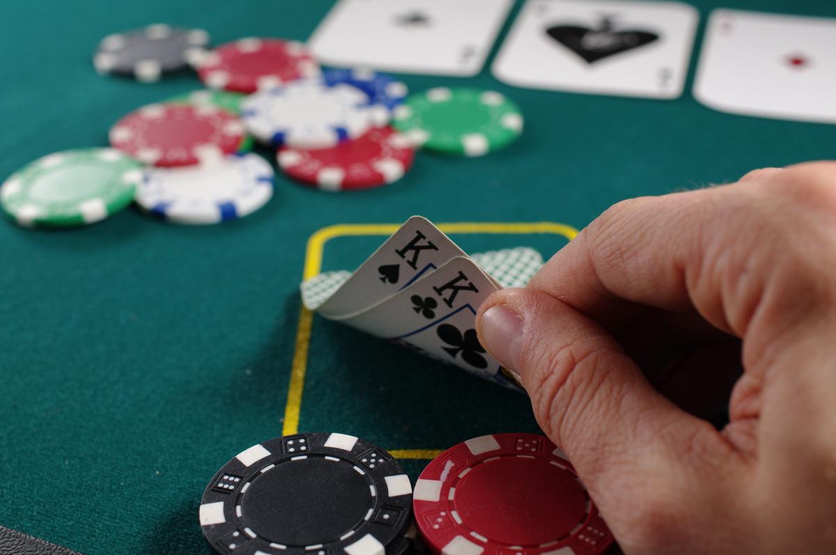 An image showing a person holding playing cards and casino chips, representing progressive betting strategies.